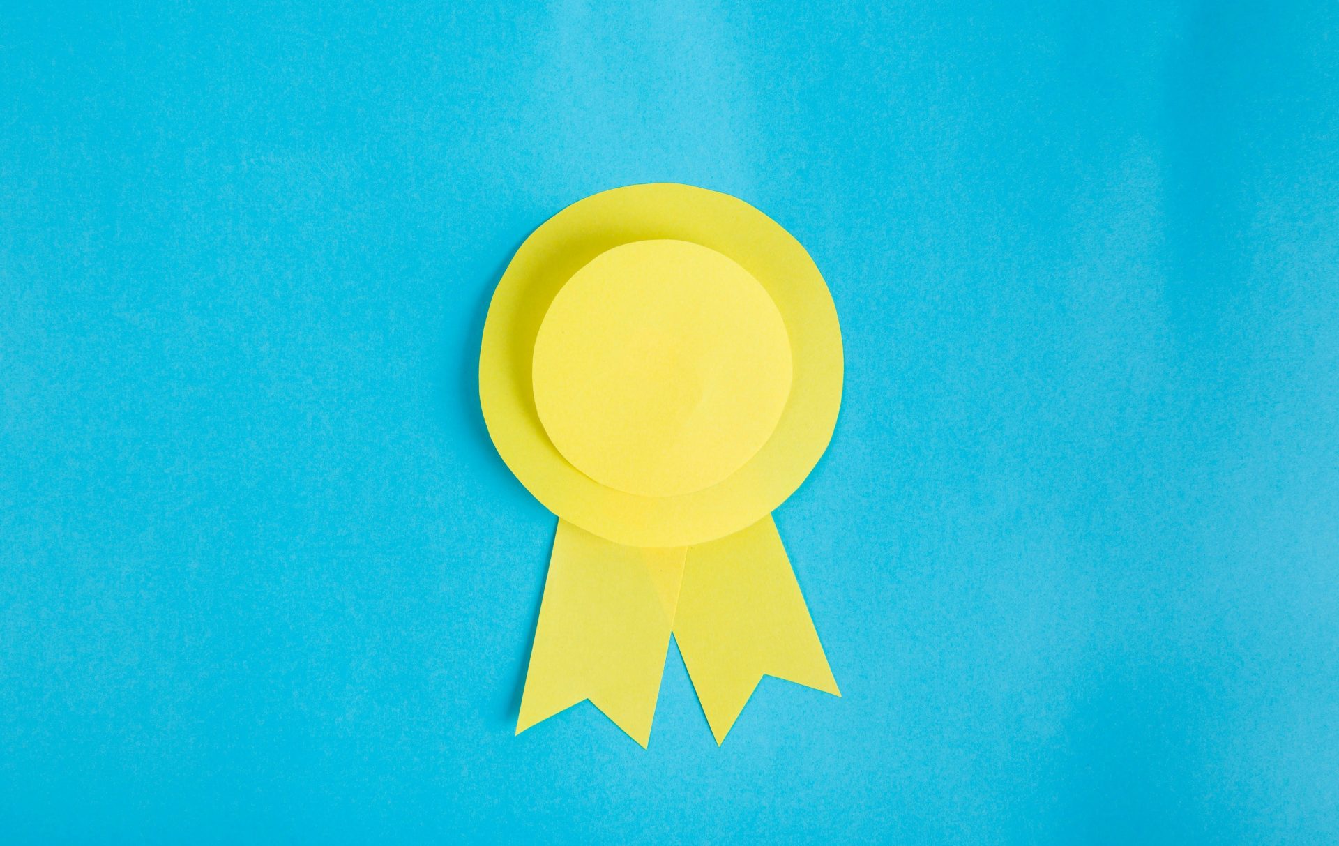 A yellow paper award ribbon on a bright blue background